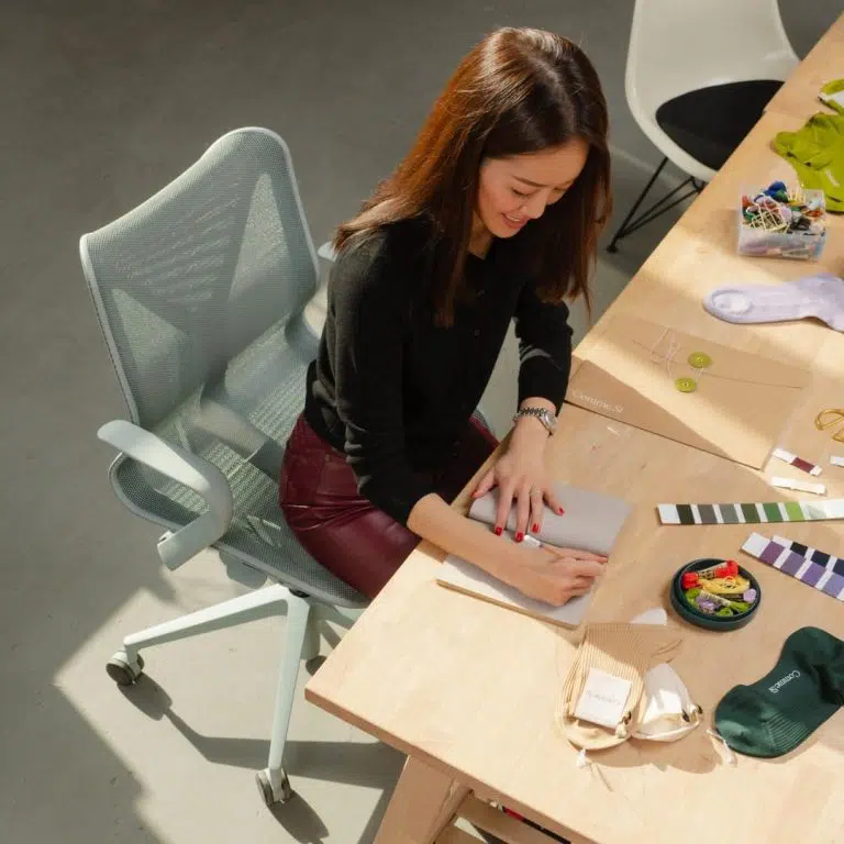tipos de ergonomia - mulher sentada em uma cadeira Cosm escrevendo