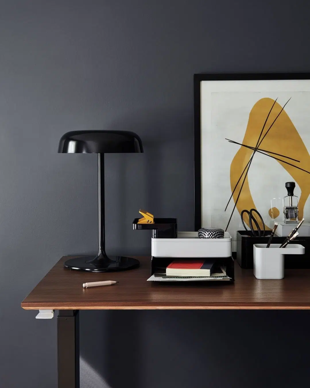 mesa com luminária, quadro e objetos de escritório