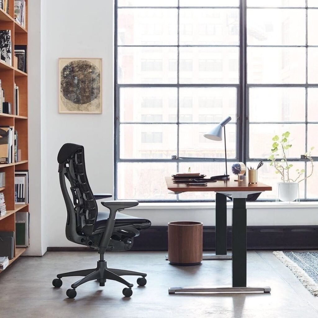Cadeira Embody Herman Miller na cor preta, em ambiente de home office com mesa de regulagem de altura Ratio com pés pretos e tampo amadeirado.