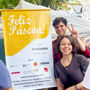Foto de voluntários da Atec Original Design junto ao banner com os parceiros envolvidos no evento e doações arrecadadas.