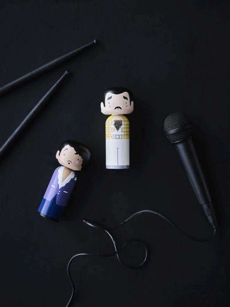 Imagem em fundo preto com kokeshi doll de Freddie Mercury e Prince.